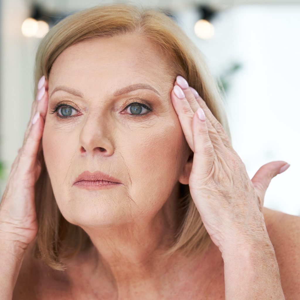 Senior woman using anti wrinkle cream in the bathroom