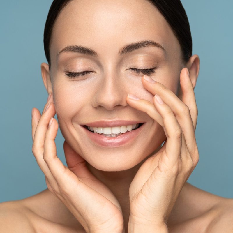 Woman with natural makeup, combed hair, touching her well-groomed pure skin on face. Anti-aging